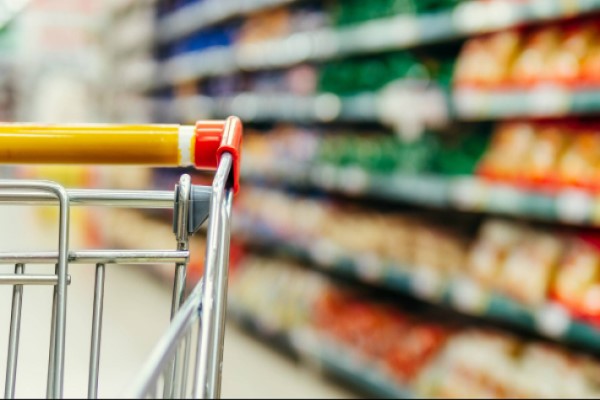 Repositor organizando produtos em gondola de supermercado pela manha