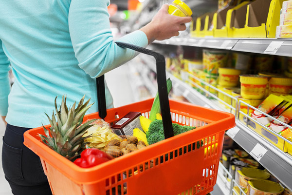 Cesta de compras de cliente em mercadinho independente com arroz, feijão, óleo, leite, pão e banana